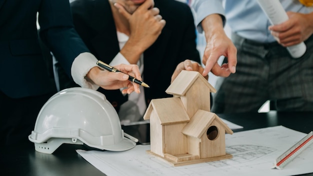 Nahaufnahme eines maßstabsgetreuen Modellhauses auf dem Tisch mit Architekten Zwei Architekten, die gemeinsam ein Architekturmodell im Büro erstellen, um ein neues Gebäude zu bilden