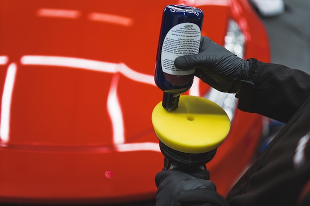 Foto nahaufnahme eines mechanikers, der einem exzenterpolierer flüssigkeit hinzufügt, um sie in der werkstatt an einem auto zu verwenden