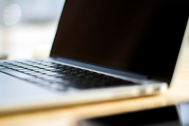 Foto nahaufnahme eines modernen laptops auf einem holztisch im sonnigen innenraum. geschäfts- und technologiekonzept