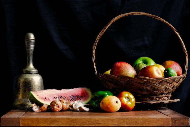 Nahaufnahme eines Obstkorbs auf einem Holztisch auf schwarzem Hintergrund