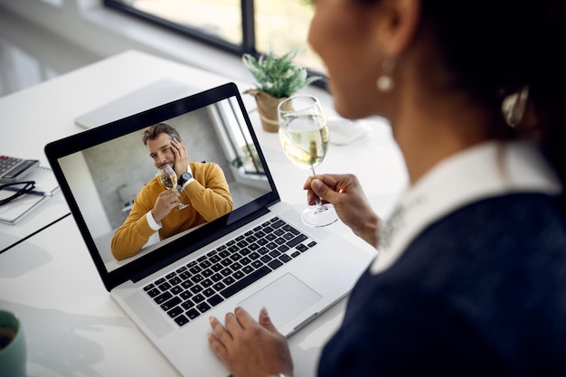 Nahaufnahme eines Paares, das Wein trinkt, während es ein Online-Date über einen Laptop hat