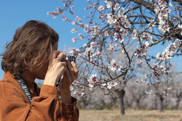 Nahaufnahme eines Porträts junger Männer, die mit einer Filmkamera Makroaufnahmen zu Blumen machen