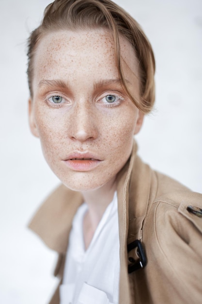 Nahaufnahme eines Portraits einer Frau mit Sommersprossen im Gesicht vor weißem Hintergrund