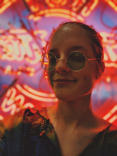Nahaufnahme eines Portraits einer Frau mit Sonnenbrille gegen beleuchtete Lichter