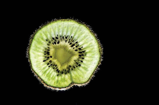 Nahaufnahme eines Querschnitts von Kiwi vor schwarzem Hintergrund