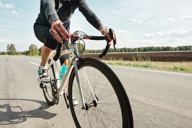 Nahaufnahme eines Radfahrers in Sportkleidung mit dem Fahrrad auf einer Landstraße