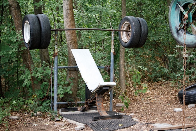 Nahaufnahme eines rauen selbstgemachten Simulators von den alten Reifen unter starken Bäumen in einem Stadtpark