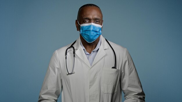 Nahaufnahme eines reifen männlichen Arztes mit Schutzmaske blickt auf einen erfahrenen Kameramann im Krankenhaus