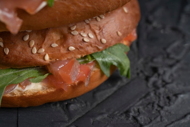 Nahaufnahme eines Sandwiches mit Lachs und Rucola auf einem dunklen Küchentisch