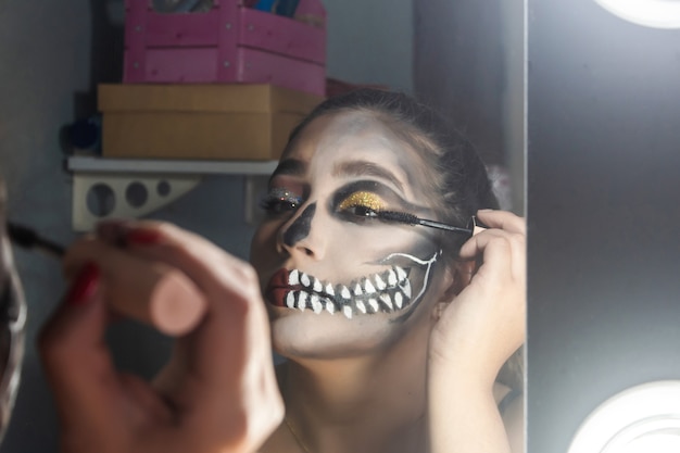 Nahaufnahme eines schönen Mädchens, das ihre Wimpern anhebt, Halloween-Make-up in ihrem Zimmer.