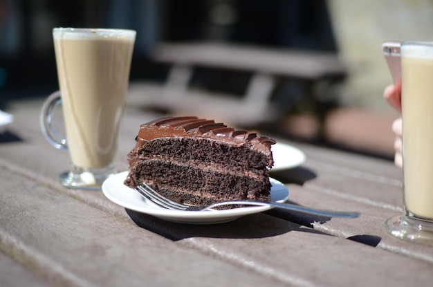 Nahaufnahme eines Schokoladenkuchens mit Latte, der auf dem Tisch im Café serviert wird