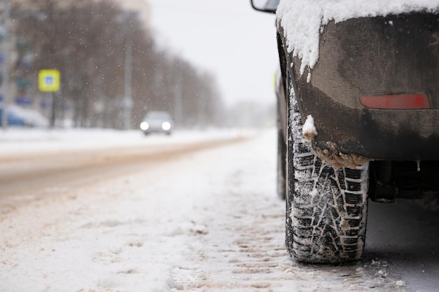 Foto nahaufnahme eines schwarzen autos mit einem beschlagenen rad auf dem hintergrund der straße und vorbeifahrender autos