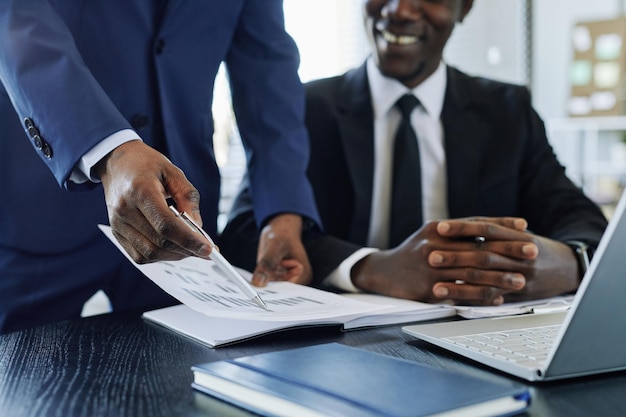 Nahaufnahme eines schwarzen Business Managers, der den Finanzbericht während eines Meetings im Bürokopierraum analysiert