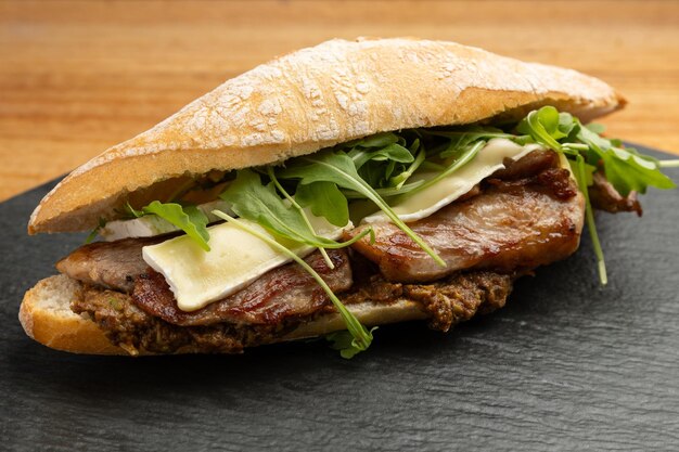 Foto nahaufnahme eines schweinefleischsandwiches mit käse und grünen trieben