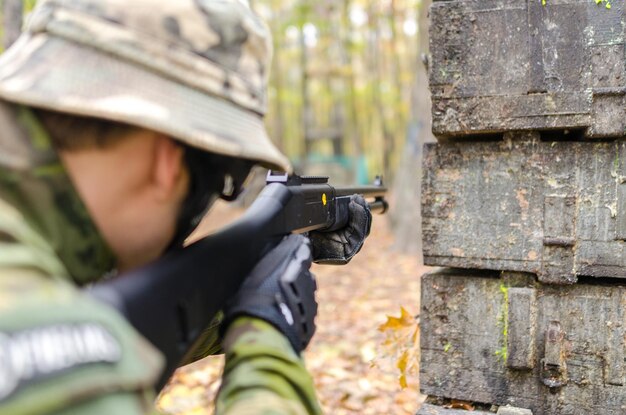 Nahaufnahme eines Soldaten, der in einem Wald mit einer Waffe zielt