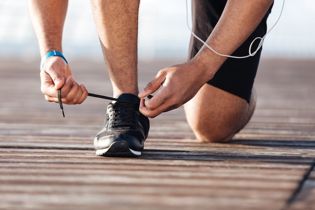 Nahaufnahme eines Sportlers schnürt seine Turnschuhe am Pier