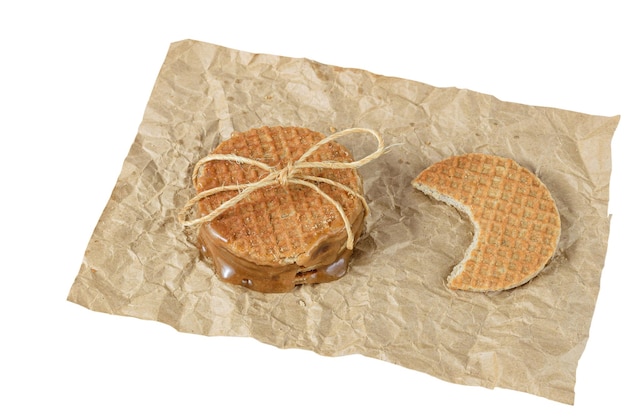 Nahaufnahme eines Stapels Stroopwafels auf braunem Papier neben einem anderen Keks mit bissweißem Hintergrund