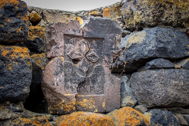 Nahaufnahme eines Steinkreuzes auf einer groben Steinmauer, Konzeptfoto, historische Gräber