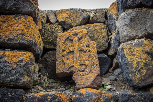 Foto nahaufnahme eines steinkreuzes mit gelber flechte auf einem rauen steinmauer-konzeptfoto