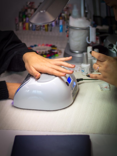 Nahaufnahme eines Stylisten, der eine Frau am Tisch Nagelkunst macht