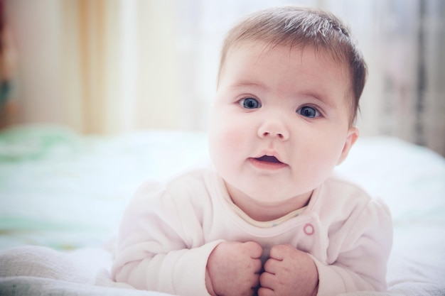 Nahaufnahme eines süßen Babys, das zu Hause auf dem Bett liegt