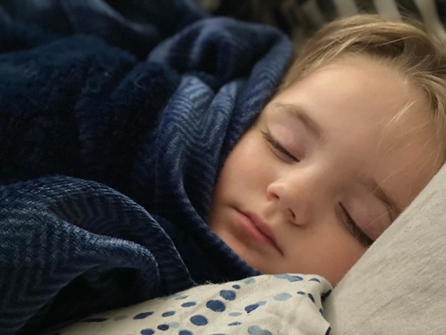 Foto nahaufnahme eines süßen jungen, der zu hause im bett schläft
