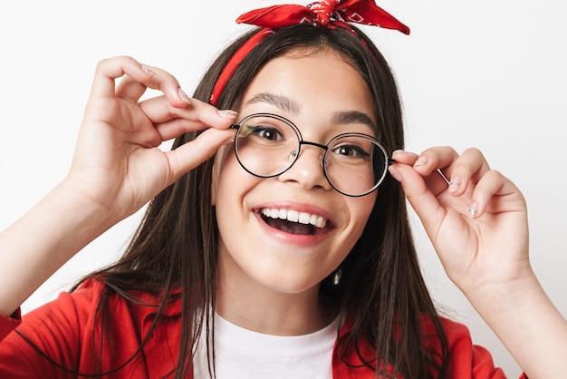 Nahaufnahme eines süßen, lustigen Teenager-Mädchens, das ein lässiges Outfit trägt, das isoliert über der weißen Wand steht und das Gesicht verzieht?