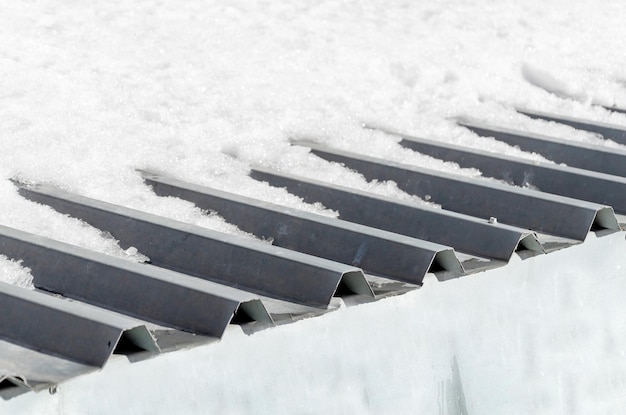 Foto nahaufnahme eines teils des daches, das mit wellenplatten bedeckt ist schnee auf dem dach im frühling schmilzt