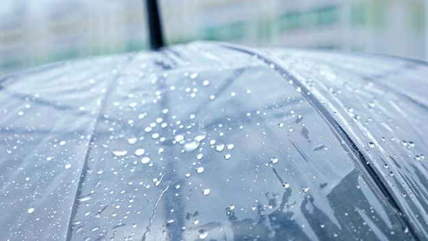 Nahaufnahme eines transparenten Regenschirms im Regen.