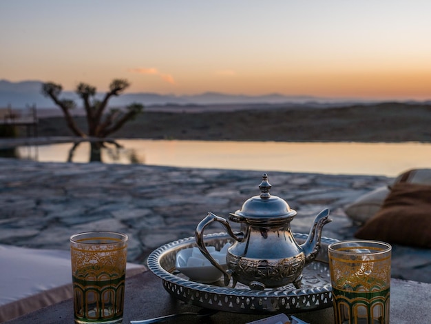 Nahaufnahme eines typischen marokkanischen Minztee-Sets auf dem Tisch in der Agafay-Wüste, Marrakesch