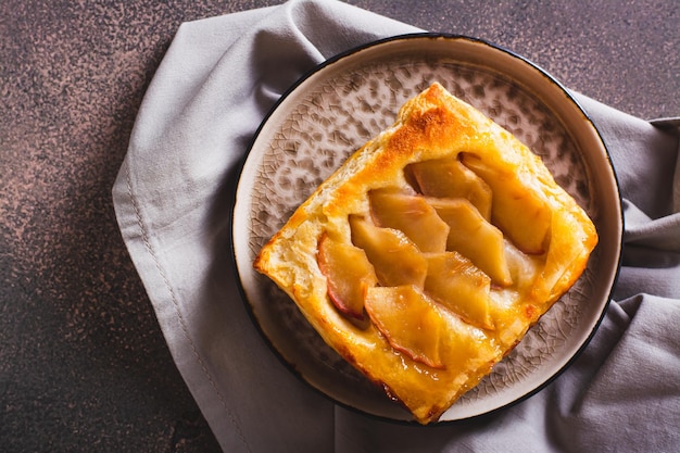 Nahaufnahme eines umgedrehten Blätterteig-Apfelkuchens auf einem Frühstücksteller von oben