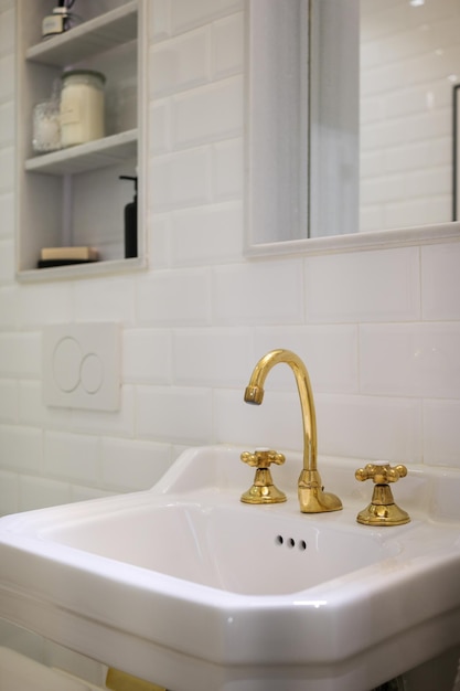 Nahaufnahme eines Vintage-Wasserhahns mit zwei Griffen in einem Badezimmer mit weißen Fliesen Kupfer-Wassermischer im Retro-Stil
