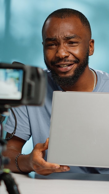 Nahaufnahme eines Vloggers, der einen modernen Laptop vor der Kamera mit Stativ überprüft. Social-Media-Influencer, der ein Gerät verwendet, um das Produkt zu überprüfen und eine Empfehlung für den Vlog-Kanal zu geben. Blogger-Aufnahmevideo