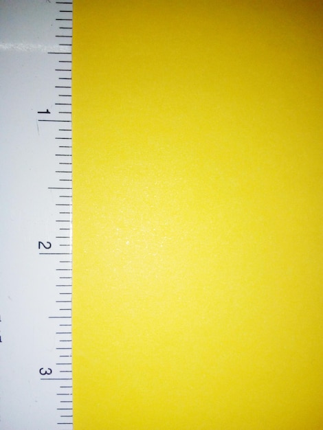 Foto nahaufnahme eines weißen lineals auf einem gelben tisch