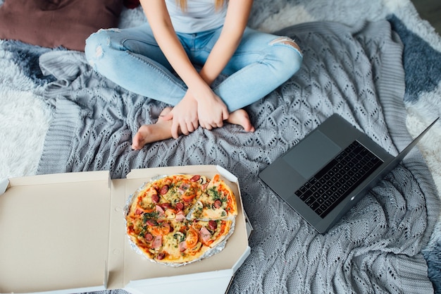 Nahaufnahme Foto aus Mädchen mit Pizza, Frau sitzt auf einem Bett.