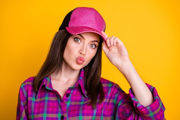 Nahaufnahme Foto einer hübschen coolen Dame, die Lippen küsst, die Sie am Arm halten, Kopfbedeckungen isoliert auf gelbem Hintergrund