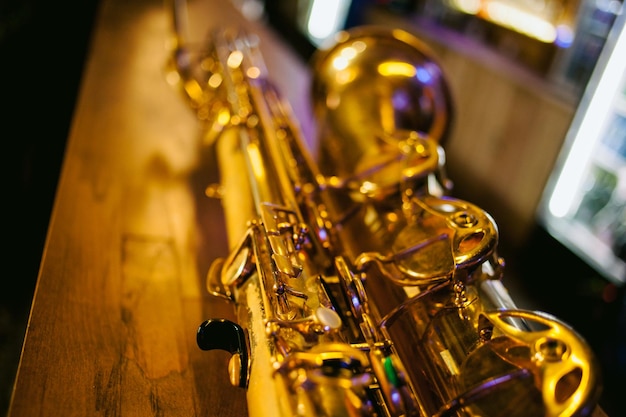 Nahaufnahme Foto eines glänzenden goldenen Saxophons. Vintage-Saxophon. Goldenes Sopransaxophon. Blasmusikinstrument. Schönes goldenes Saxophon auf Holzuntergrund