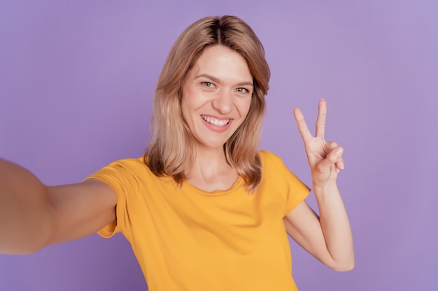 Nahaufnahme Foto schöne Frau glücklich positives Lächeln machen Selfie Show Peace V-Zeichen isoliert über lila Farbe Hintergrund