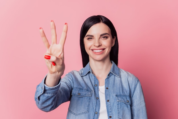 Nahaufnahme foto schönes mädchen glückliches positives lächeln halten hand arm zählend drei isoliert rosa heller hintergrund