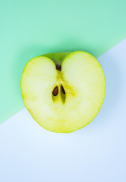 Nahaufnahme Foto von Green Apple Fruit auf dem weißen und grünen Hintergrund Ursprüngliches und kreatives Bild des Minimalismus Schöne natürliche Tapete