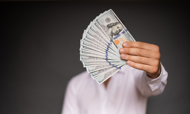 Nahaufnahme Foto von jungen männlichen Händen halten die vielen Dollar der USA isoliert auf grauem Hintergrund