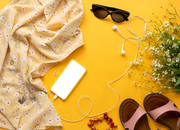 Nahaufnahme Foto von Lifestyle-Accessoires für Mädchen Stillleben von zufälligen Objekten einer modernen Mädchenfrau Blumenbluse Ohrhörer Telefonohrringe Sonnenbrille Schuhe Draufsicht