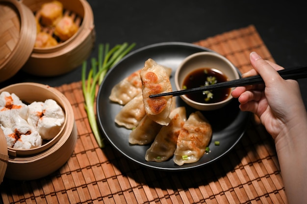 Nahaufnahme Frau, die Gyoza oder gebratene Knödel mit Essstäbchen im asiatischen chinesischen Restaurant isst