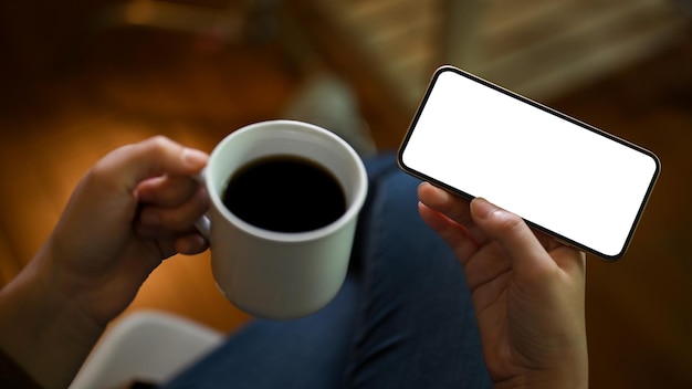 Nahaufnahme Frau, die Videos auf einer Online-Plattform per Smartphone ansieht und eine Tasse Kaffee hält