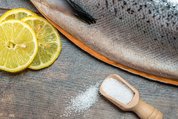 Nahaufnahme Frischer roher Lachs roter Fisch mit Gewürzen Salz Zitrone Pfeffer Rosmarin auf dunklem Holzhintergrund Lachs kochen Seefisch gesundes Essen Draufsicht