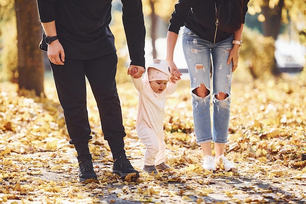 Nahaufnahme. Fröhliche Familie, die zusammen mit ihrem Kind im schönen Herbstpark Spaß hat.