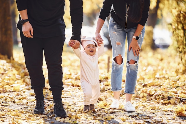 Nahaufnahme. Fröhliche Familie, die zusammen mit ihrem Kind im schönen Herbstpark Spaß hat.