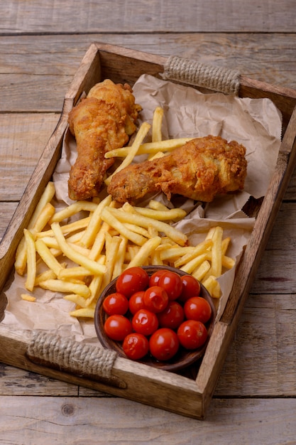 Nahaufnahme gebratene Hähnchenschenkel und Pommes Frites mit marinierten Tomaten