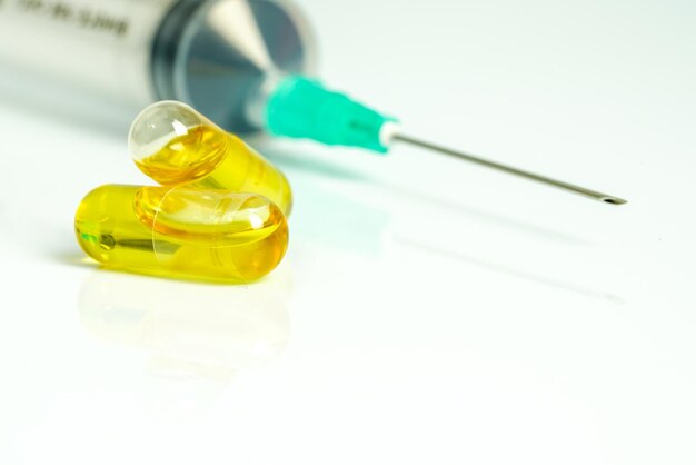 Nahaufnahme gelber Kapseln gegen die Spritze auf dem Tisch