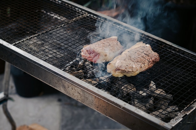 Nahaufnahme Grillen Sie das Rindfleisch auf dem Holzkohlegrill, um Steaks zu kochen.